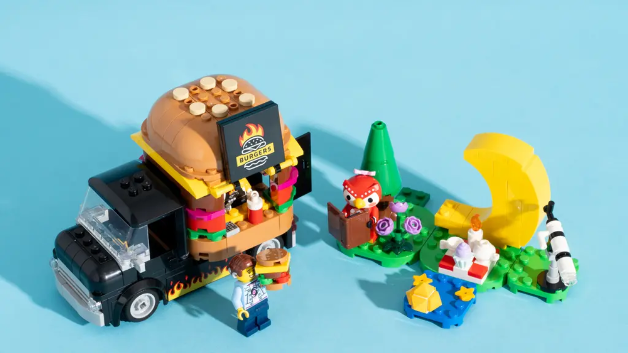 A LEGO burger van, shaped like a burger, alongside a brown owl sitting by a yellow moon 